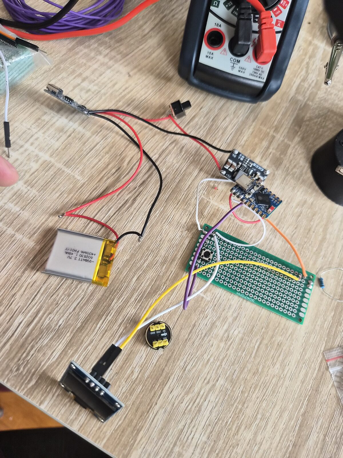 Bench wiring — TP4056, boost converter, S3, and the button on perfboard